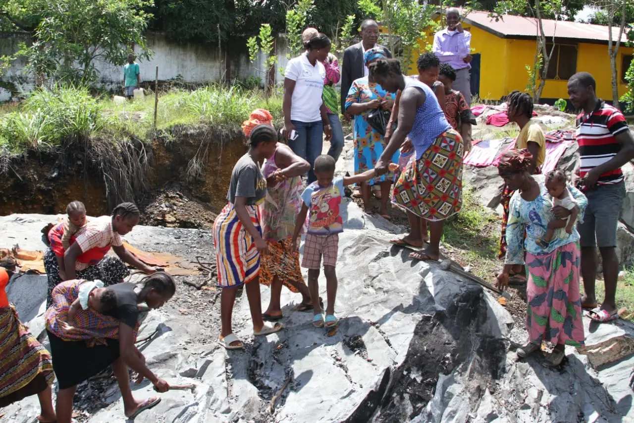 Community members with stone-filled containers and concrete blocks for construction